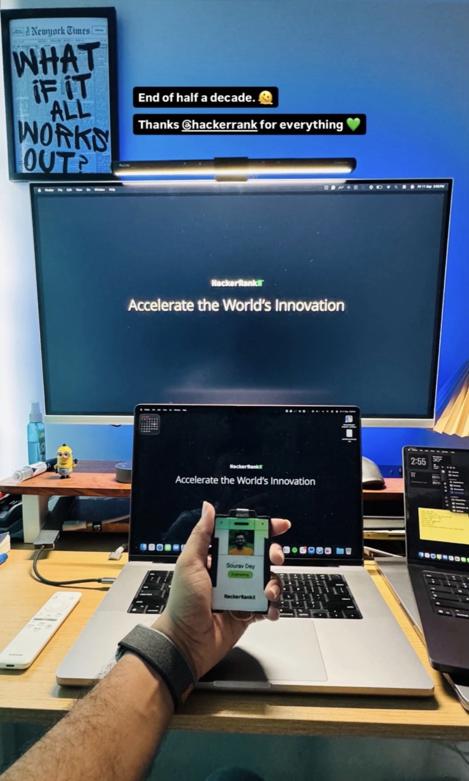 Sourav holding his HackerRank ID badge at his desk on the last day, with the HackerRank "Accelerate the World's Innovation" screen on the monitor and laptop